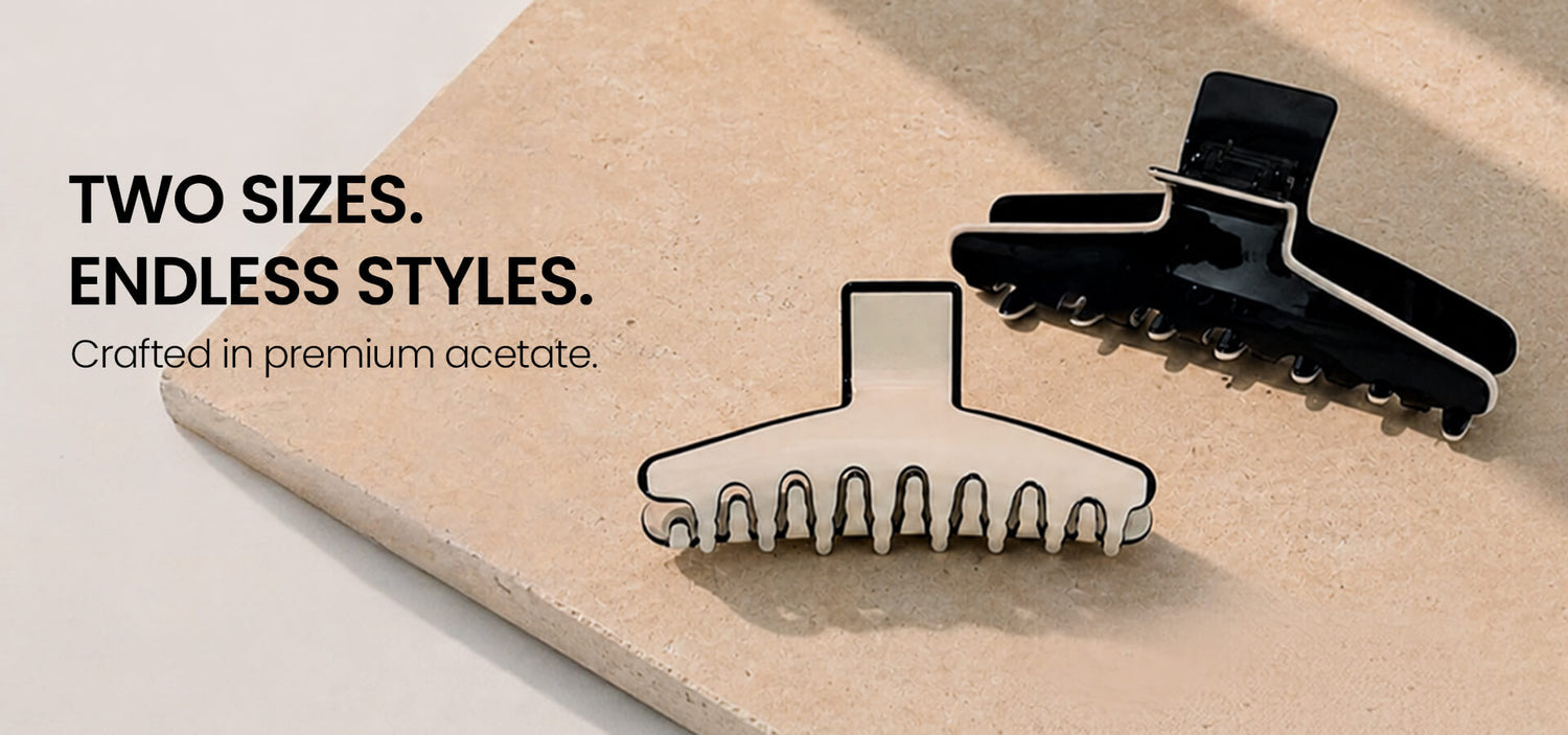 Two black and white Kendall hair clips in different sizes, crafted from premium acetate, displayed on a textured stone surface to highlight their elegant and versatile styling capabilities.