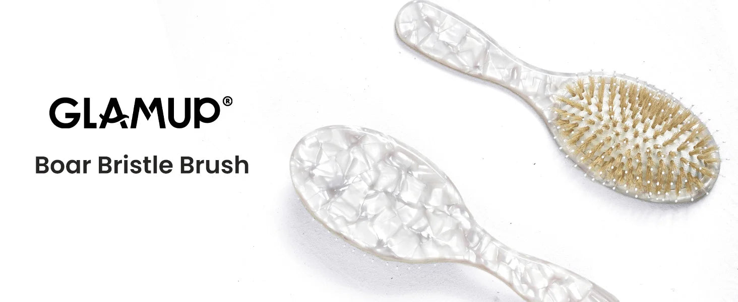 Two GLAMUP Boar Bristle Brushes shown on a white background, one upright to display the clear textured handle and bristle pad, and one angled to show the clear textured handle from another side. The brand name 'GLAMUP' is printed on the left.