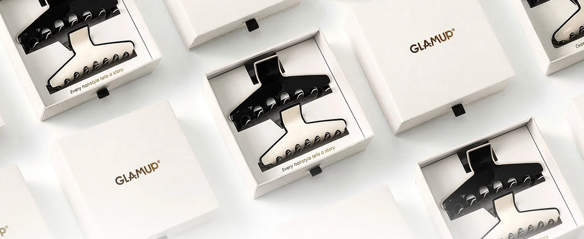 Top-down studio view of GLAMUP The Kendall large acetate claw clip packaged neatly in luxury branded gift boxes for gifting.