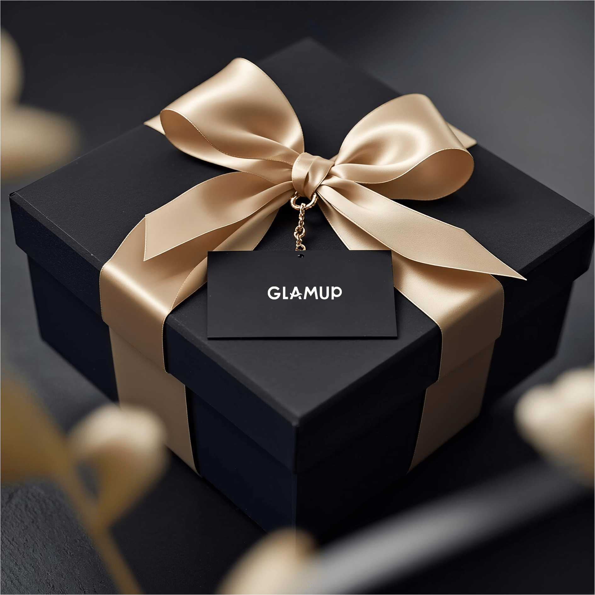 Black gift box with a gold ribbon and 'GLAMUP' tag on a dark background