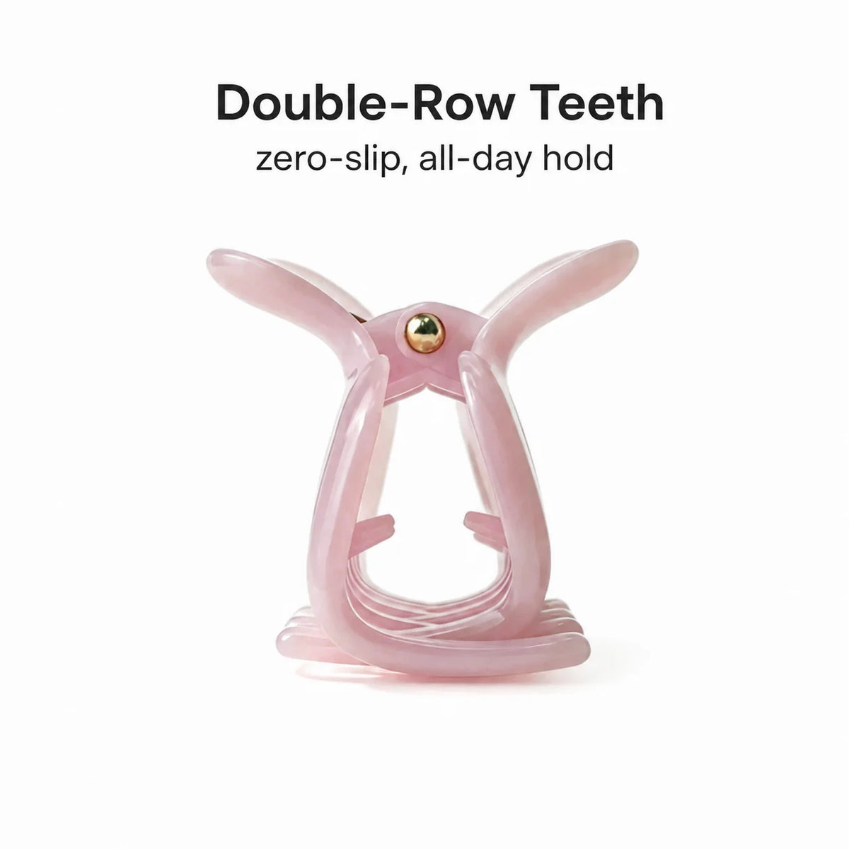 A translucent light pink double-row hair clip with a small gold metal center screw, shown on a white background with the text 'Double-Row Teeth zero-slip, all-day hold' above it.