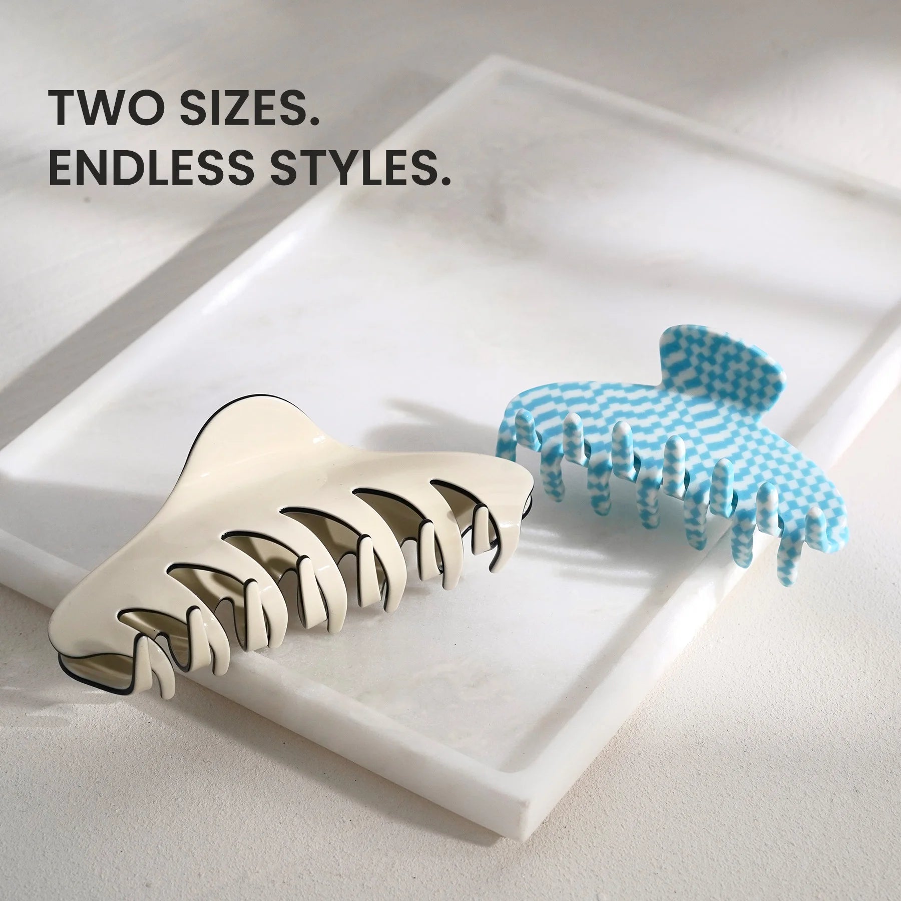Two sizes of the Glamup claw clip set displayed on a marble tray, highlighting extra large XL size options for versatile styling.