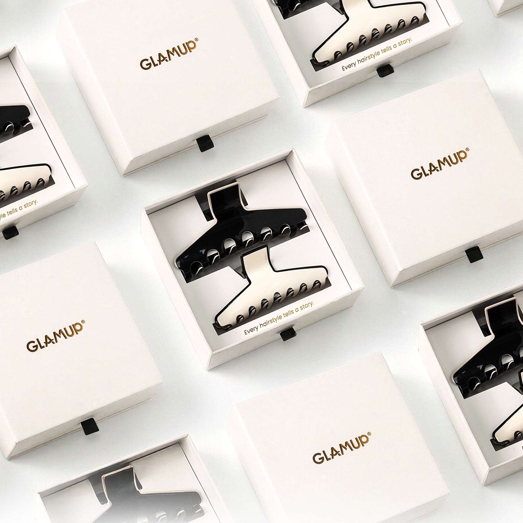 Top-down view of multiple GLAMUP acetate claw clip units neatly arranged in luxury branded gift boxes.